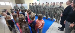Dzieci stoją naprzeciwko młodzieży w mundurach wojskowych