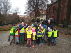 Grupa dzieci z nauczycielką stoją przy pomniku Mikołaja Kopernika