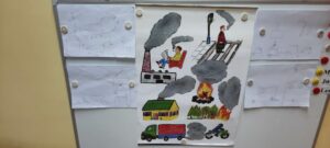 na tablicy magnetycznej znajduje się plansza ze źródłami dymu, po obu stronach obrazki dzieci ze źródłami dymu zaobserwowanymi podczas spaceru 