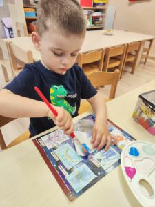 Chłopiec maluje na niebiesko serce wykonane z masy porcelanowej.