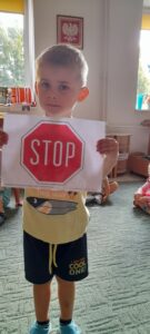 Chłopiec trzyma w ręku obrazek ze znakiem drogowym STOP