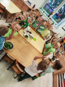 Grupa dzieci przy stole trzymająca ogórki