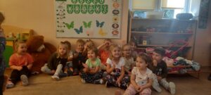 Grupa dzieci siedzi na dywanie, w tle napis "dzień kropki"