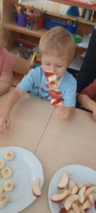 Chłopiec nakłada kawałki owoców na drewniany patyczek do szaszłyków 