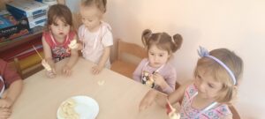 Kilkoro dzieci nakłada kawałki owoców na drewniane patyczki do szaszłyków 
