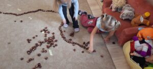 Dziewczynki układające kasztany na dywanie 
