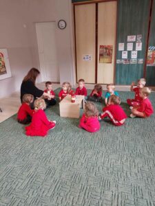 Nauczycielka i grupa dzieci siedzący na dywanie.
