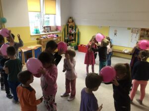 Dzieci tańczące w parach z balonami przy czole.