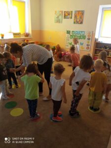 Grupa dzieci stoi na kolorowych okrągłych krążkach 