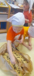 Chłopiec sypiący pestki po cieście chlebowym.