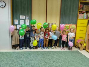 Grupa dzieci stojąca przy szafie z kolorowymi balonami.