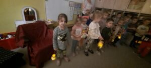Grupa dzieci trzyma w dłoniach papierowe lampiony