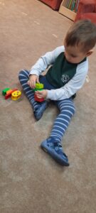 Chłopiec siedzi na dywanie trzymając w dłoniach klocki