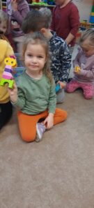 Dziewczynka siedzi na dywanie trzymając w dłoniach klocki