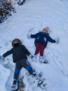Chłopiec i dziewczynka wykonujący aniołki na śniegu.
