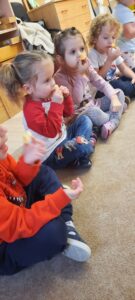 Kilkoro dzieci siedzi na dywanie w dłoniach trzymając kawałek cytryny 
