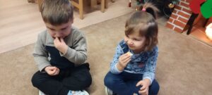 Dziewczynka i chłopiec siedzą na dywanie smakując cytrynę 