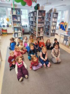 Grupa dzieci siedząca na dywanie w Bibliotece.