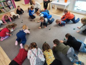 Grupa dzieci podczas zabaw oddechowych z piórkami.