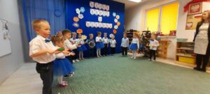 Grupa dzieci gra na instrumentach podczas występu z okazji Dnia Babci i Dziadka.