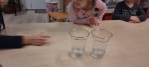 Dwa plastikowe kubki z wodą stojące na stoliku 