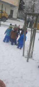 Grupa dzieci wsypuje ziarna do karmnika 