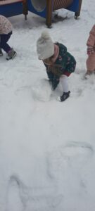 Dziewczynka toczy kule śnieżną 