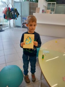 chłopiec trzyma w ręku pracę plastyczną pt. "Wielkanocna wydzieranka"
