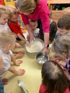 Nauczycielka wraz z dziećmi przygotowuje masę solną.