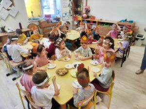 Przedszkolaki siedzące przy stolikach, zajadające tort.
