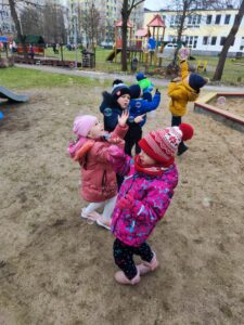 Dzieci w ogrodzie przedszkolnym podczas zabawach ruchowych z bańkami mydlanymi.