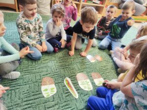 Grupa dzieci układająca plansze na dywanie "Od nasionka do roślinki"