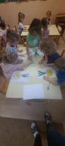 Dzieci siedzą przy stoliku wyklejając obrazek cebuli 