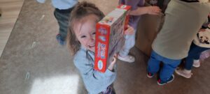 Dziewczynka trzyma w dłoniach kolorowe pudełko 