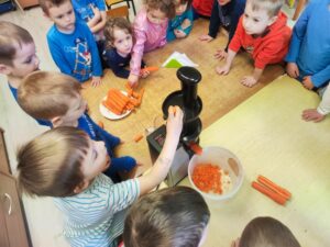 Grupa dzieci przygotowująca zdrowy sok marchwiowy.