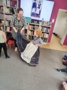 Dziewczynka przymierzająca tradycyjny strój warmiński w Bibliotece.