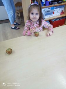 Dziecko siedzi przy stoliku dekorując pisakiem babeczkę