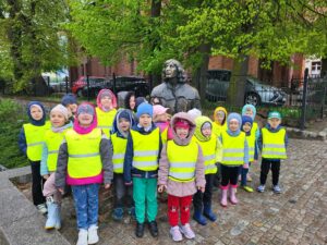 grupa dzieci stoi przed pomnikiem Mikołaja Kopernika