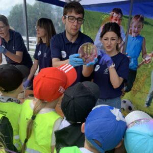 grupa dzieci w odblaskowych kamizelkach oglądająca bakterie