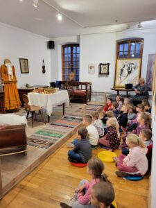 Dzieci siedzące  w sali muzeum