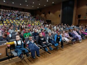 Dzieci siedzące wraz z opiekunami w auli