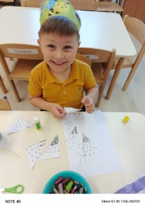 Chłopiec w opasce przedstawiającej pszczołę, siedzi przy stoliku i układa puzzle pszczoły