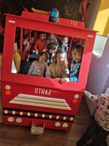 Przedszkolaki w wozie strażackim na sali edukacyjnej.