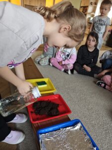 Dziewczynka nalewająca wodę do ziemi ogrodowej