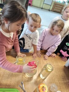 Dziewczynka dolewająca do dzbanka z wodą sok z cytryny