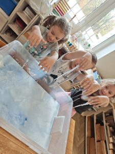 Dwie dziewczynki i chłopiec podczas zabawy cieczą