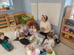 Nauczycielka pokazująca dzieciom zimową ilustracje oraz pożywienie dla ptaków