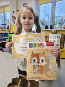 Dziewczynka trzyma w dłoniach dyplom i książkę