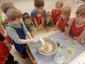 Grupa dzieci przygląda się chłopcu trzymającemu mikser.