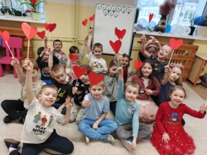 Dzieci siedzące na dywanie i trzymające serduszka na patyczku